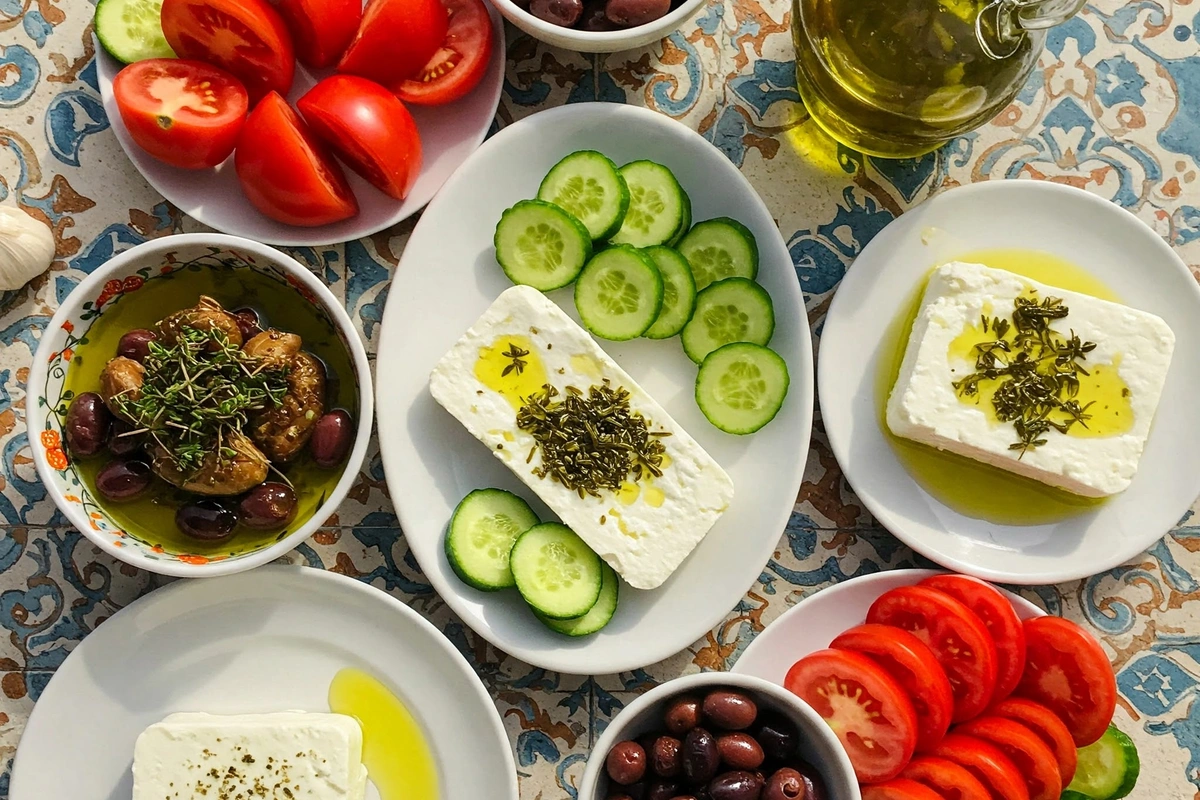 Mediterranean table spread with feta cheese, vegetables, and olives